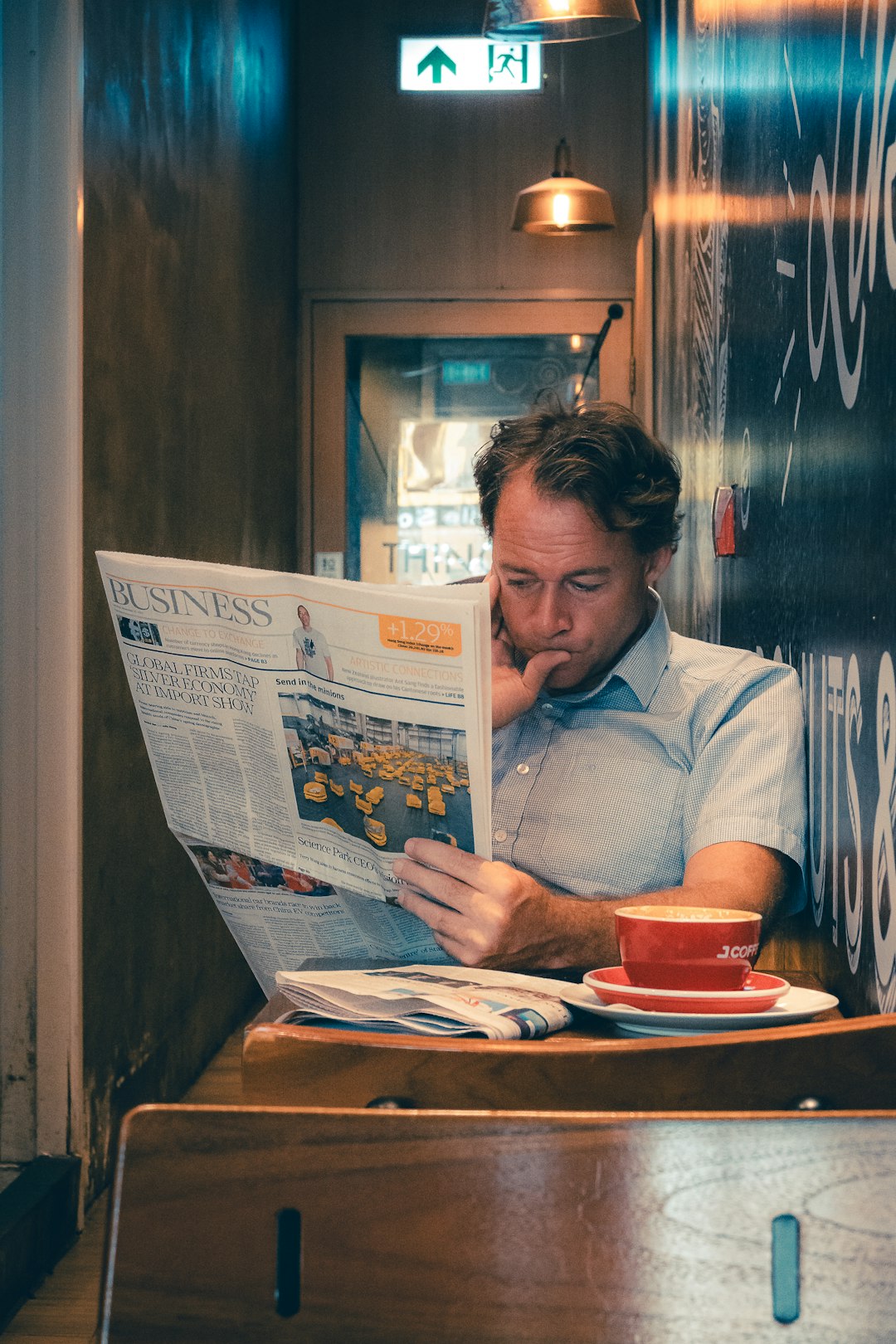 man-reading-newspaper-with-coffee-at-cafe-em40er-i88y